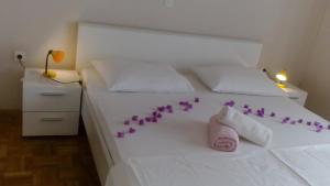 um quarto com uma cama branca com flores roxas em Apartments Katarina em Sveti Petar