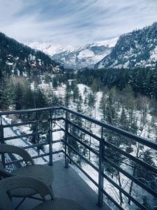 a balcony with a view of a snow covered mountain at Hidden Heaven Waterfall view in Manāli