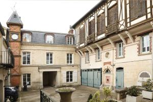 an old building with a clock tower and a courtyard at Le jardin de L'Hippodrome in Chantilly