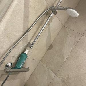 a shower head with a green bottle of toothpaste at Le jardin de L'Hippodrome in Chantilly +39 photos
