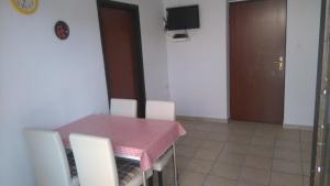une salle à manger avec une table rose et des chaises blanches dans l'établissement Apartments Krešo, à Starigrad-Paklenica