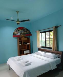 a bedroom with a large bed with a blue wall at KODO Guest House in Nathon Bay