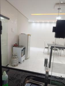 a white kitchen with a refrigerator and a table at SSP Ubajara in Ubajara