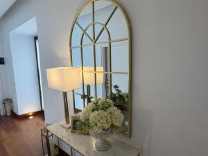 a mirror on a wall next to a table with flowers at Hotel Boutique Palacio del Moral in Ronda
