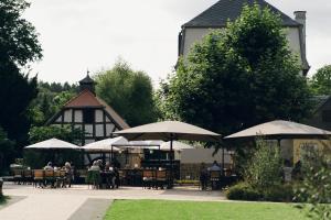 people sitting at tables with umbrellas in front of a building at Hofgut Schmitte in Gießen