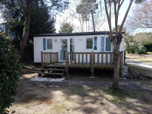 a tiny house with a porch and two benches at Camping Les Pins de Sel in Saint-Augustin