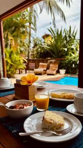 a table with plates of food and a glass of orange juice at Pousada Casa de Inaê in Itacaré