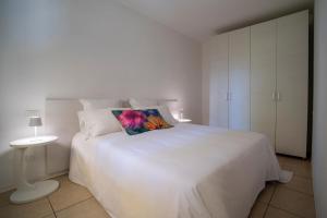a white bedroom with a white bed with a flower pillow at Casa Battaglia in Cavallino-Treporti