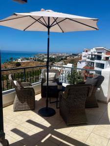a patio with chairs and an umbrella on a balcony at Best Vistamar Sea View in Torrox Costa