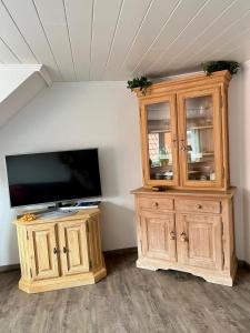a large wooden entertainment center with a flat screen tv at Dat Kapitänshuus in Carolinensiel +24 photos