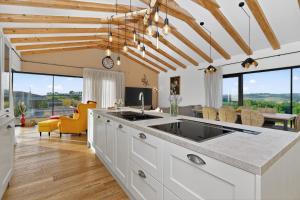 a kitchen with white cabinets and a dining room with windows at Villa Sanpadeo by Rent Istria in Brtonigla