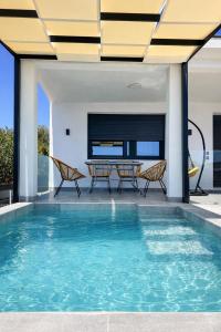an indoor swimming pool with a table and chairs at Mirage Luxury Living in Nea Potidaea