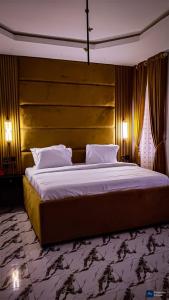 a bedroom with a large bed with a wooden headboard at Enuana Hotel And Suite in Odobor