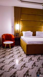 a hotel room with a bed and a chair and a table at Enuana Hotel And Suite in Odobor