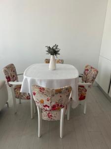 a white table with chairs and a vase with flowers at Hij Apartaments in Rădăuţi