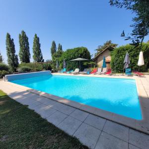 a swimming pool in a yard with chairs and umbrellas at Studio cosy au calme in Chillac