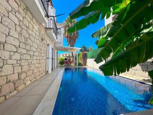 a swimming pool in front of a building with blue water at Evalacati-Villa Palma-Central villa with private pool and garden in Çeşme