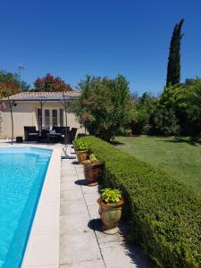 a row of potted plants next to a swimming pool at " Chez NADOU " 2 Chambres d' Hôtes dans maison indépendante à 4 Kms d'Uzès in Arpaillargues-et-Aureillac