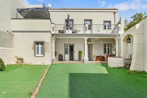 a large white house with a green lawn at Luxar Suites & Apartments in Assemini