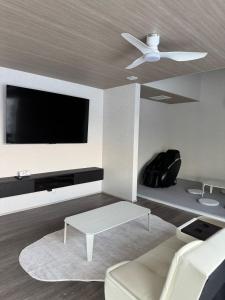 a living room with a ceiling fan and a tv at VILLA TSUKUNAMI aoshima in Miyazaki