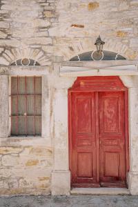 a red door and a window on a stone building at Alternative Medieval Villa in Kalamoti