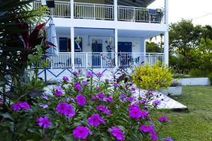 a white house with purple flowers in the yard at VILLA EDEN Gosier in Le Gosier