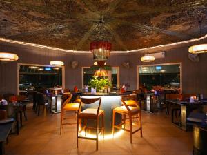 a restaurant with tables and chairs and a chandelier at The Solluna Resort in Marchula