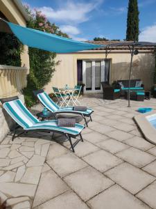 two lounge chairs and an umbrella on a patio at " Chez NADOU " 2 Chambres d' Hôtes dans maison indépendante à 4 Kms d'Uzès in Arpaillargues-et-Aureillac