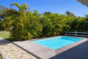 a swimming pool in a backyard with palm trees at Villa Bel Plaisi 3 chambres piscine privée Le Moule in Le Moule