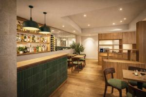 a restaurant with a green bar with tables and chairs at Hôtel de l'Horloge in Avignon