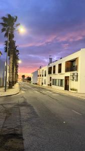 an empty street with a building and a palm tree at Calmaria Guesthouse in Porto Covo