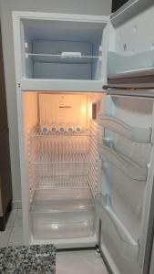 an empty refrigerator with its door open in a kitchen at Quarto Casal Com AR Condicionado e Banheiro Privativo in Guaíra