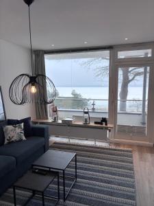 a living room with a blue couch and a large window at Ostseeblick Apartment 2 in Scharbeutz