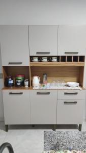 a kitchen with white cabinets and a counter at Quarto Casal Com AR Condicionado e Banheiro Privativo in Guaíra