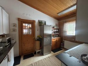 a kitchen with a stainless steel refrigerator and wooden ceilings at Villa Sillankorva in Viitasaari
