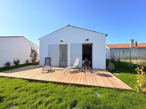 a deck with two chairs and a table in a yard at Les Alizés, 3 étoiles in La Brée-les-Bains