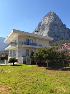 a white house with a mountain in the background at Villa Leom - Mountain Villa with Pool in Antalya in Gedeller
