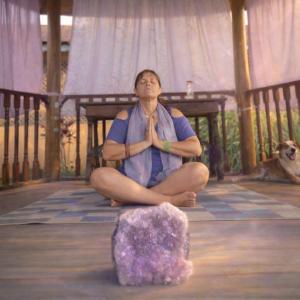 a woman sitting in a yoga pose next to a rock at Pousada Atelier Aly da Costa in Iguape