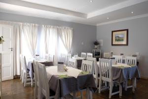 a dining room with white tables and white chairs at Firwood Lodge in Pretoria