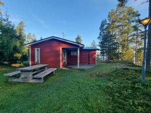 a small red cabin with a picnic table in the yard at Narvijärven lomamökki in Rauma