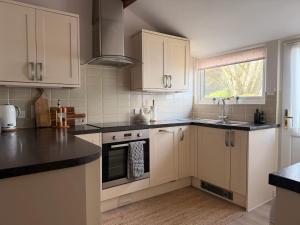a kitchen with white cabinets and black counter tops at The View Cottage - Tennis Court - Nr Frome, Longleat in Frome