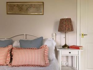 a bed with pillows and a lamp on a table at The View Cottage - Tennis Court - Nr Frome, Longleat in Frome