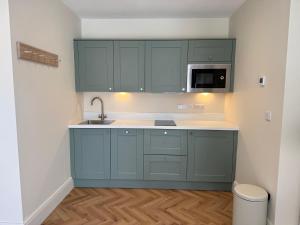 a kitchen with blue cabinets and a sink at Lillypool Farm in Shipham +15 photos