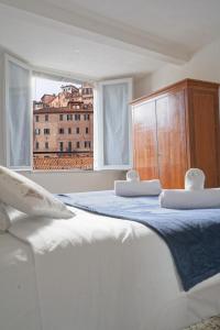 a white bedroom with two beds and a window at Gest Short Rent Siena 4 in Siena