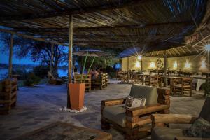 un restaurant avec des chaises, des tables et un parasol dans l'établissement Big 5 Toro Lodge, à Kasane