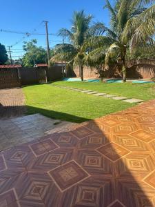 a patio with a lawn with palm trees at Pousada Jangarelli in Guaíra