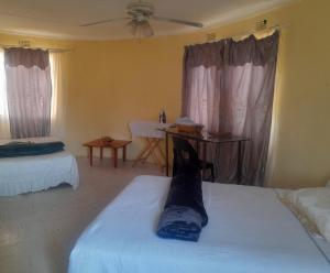 a living room with two beds and a ceiling fan at The Oval House in Otse