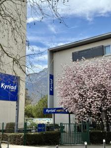 a building with a flowering tree in front of a building at Kyriad Grenoble Centre in Grenoble