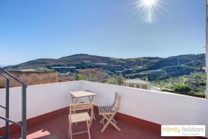 a balcony with two chairs and a table on a roof at Homity Holidays - Gualchos - Casa Río Oculto in Gualchos