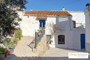 a white house with a blue door on a street at Homity Holidays - Gualchos - Casa Río Oculto in Gualchos